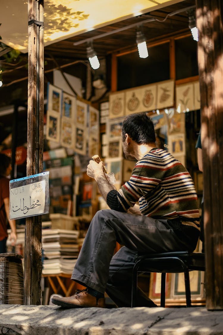 Man Sitting On Chair Near Outdoor Stand