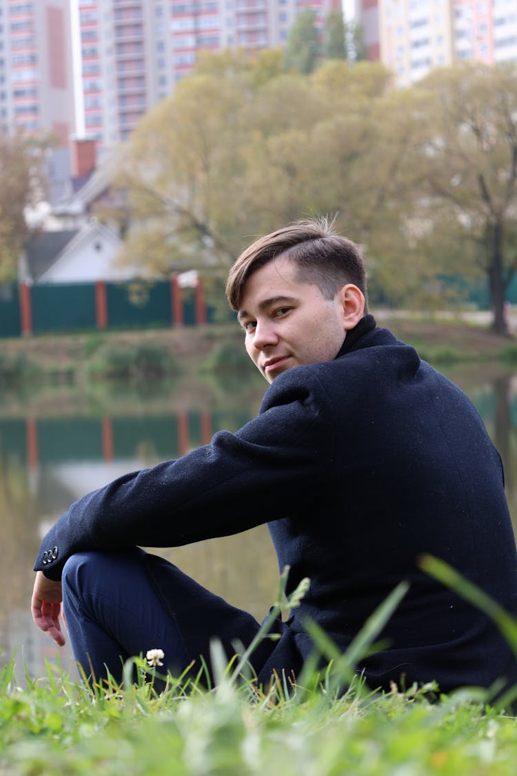 Man Sitting On River Bank In City