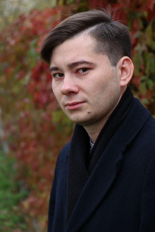 Free Portrait of a man in a coat with autumn leaves in the background, conveying a stylish autumn vibe. Stock Photo