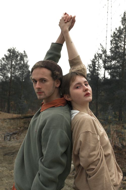 Free Young couple standing back to back with their hands raised in a serene outdoor setting. Stock Photo