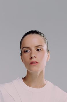 Elegant portrait of a woman in white blouse, looking contemplatively to the side against a light background.