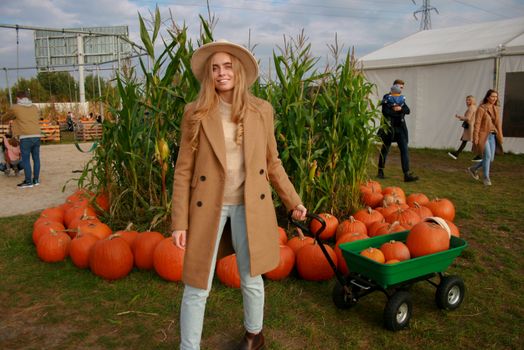 Young woman in a fall setting with pumpkins and corn, enjoying a day outdoors.