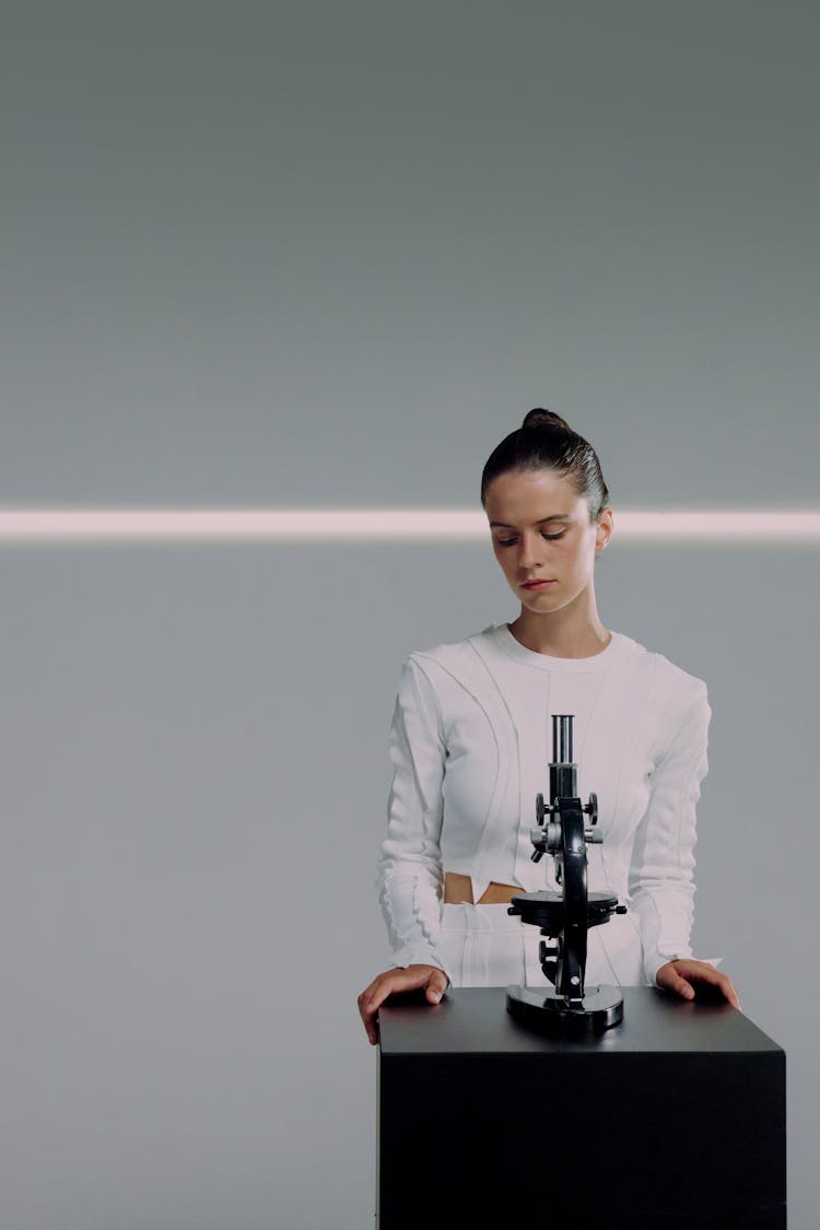 A Female Scientist Standing Behind A Microscope