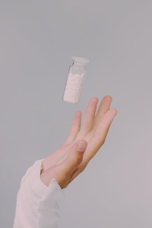 Free A hand below pill vial mid-air Stock Photo