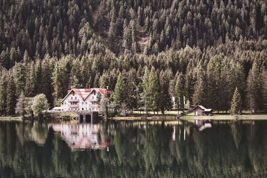 Tranquil lakeside scene with a cozy cabin surrounded by lush forest reflections.