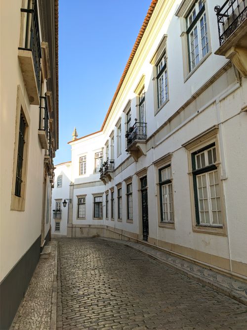 Free Idyllic narrow alley in historic city with elegant white buildings and wooden windows. Stock Photo