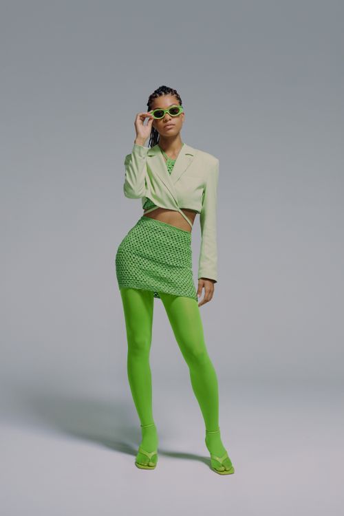 Free Stylish adult woman posing in green fashion outfit with sunglasses in a studio. Stock Photo