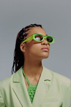 Portrait of a confident woman in green attire and sunglasses, looking upward.