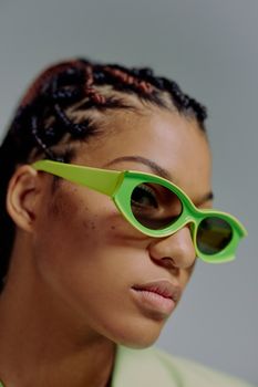 Close-up portrait of a fashionable woman wearing vibrant green sunglasses, highlighting modern style.