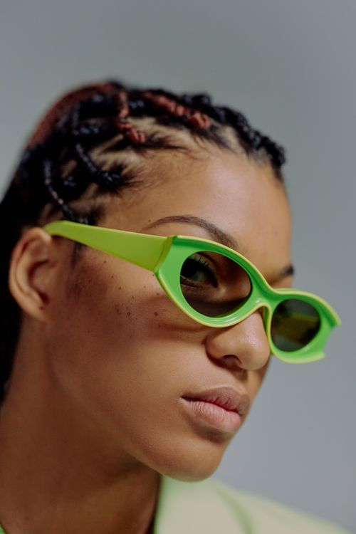 Free Close-up portrait of a fashionable woman wearing vibrant green sunglasses, highlighting modern style. Stock Photo
