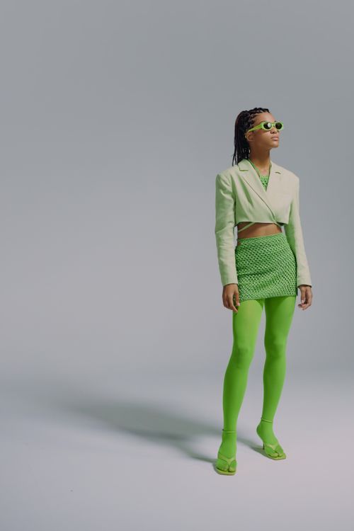 Free Stylish woman in green attire posing against a gray background in a studio setting. Stock Photo