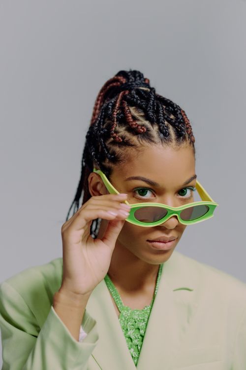 Free Portrait of a fashionable woman in green sunglasses against a gray background. Stock Photo