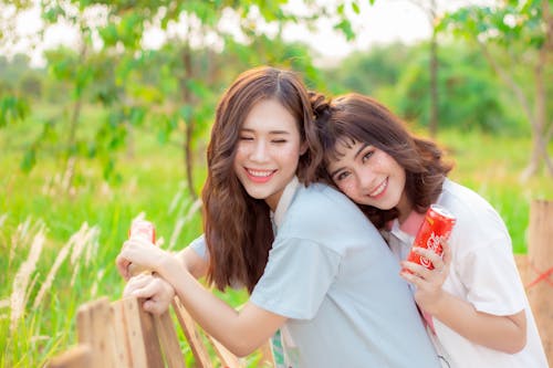 Free Women Smiling Together while Holding a Canned Drink Stock Photo