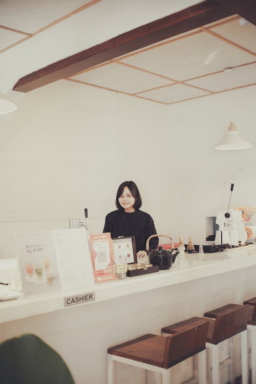 Woman in Black Long Sleeve Shirt Standing Behind a Bar Counter