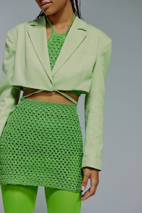 Free Chic fashion featuring a green jacket, crochet top, and matching skirt with stockings. Stock Photo