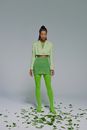 Portrait of woman in green clotheswith leaves on floor
