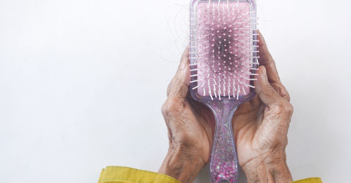 Close-up of senior hands holding a hairbrush with hair strands against a white backdrop. - Evidence evidence guide for selenium hair loss meta-analysis