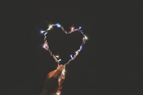 Person Holding Multicolored Heart-shaped String Lights