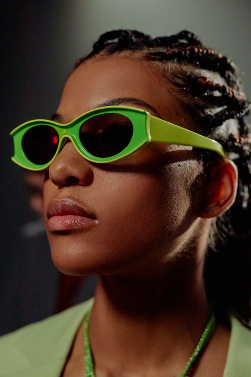 Free A modern fashion studio portrait featuring a woman in bright green sunglasses, exuding a futuristic vibe. Stock Photo