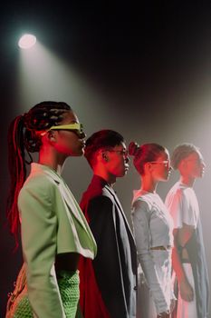 A stylish group of young adults in trendy attire posing under a dramatic spotlight at a studio fashion shoot.