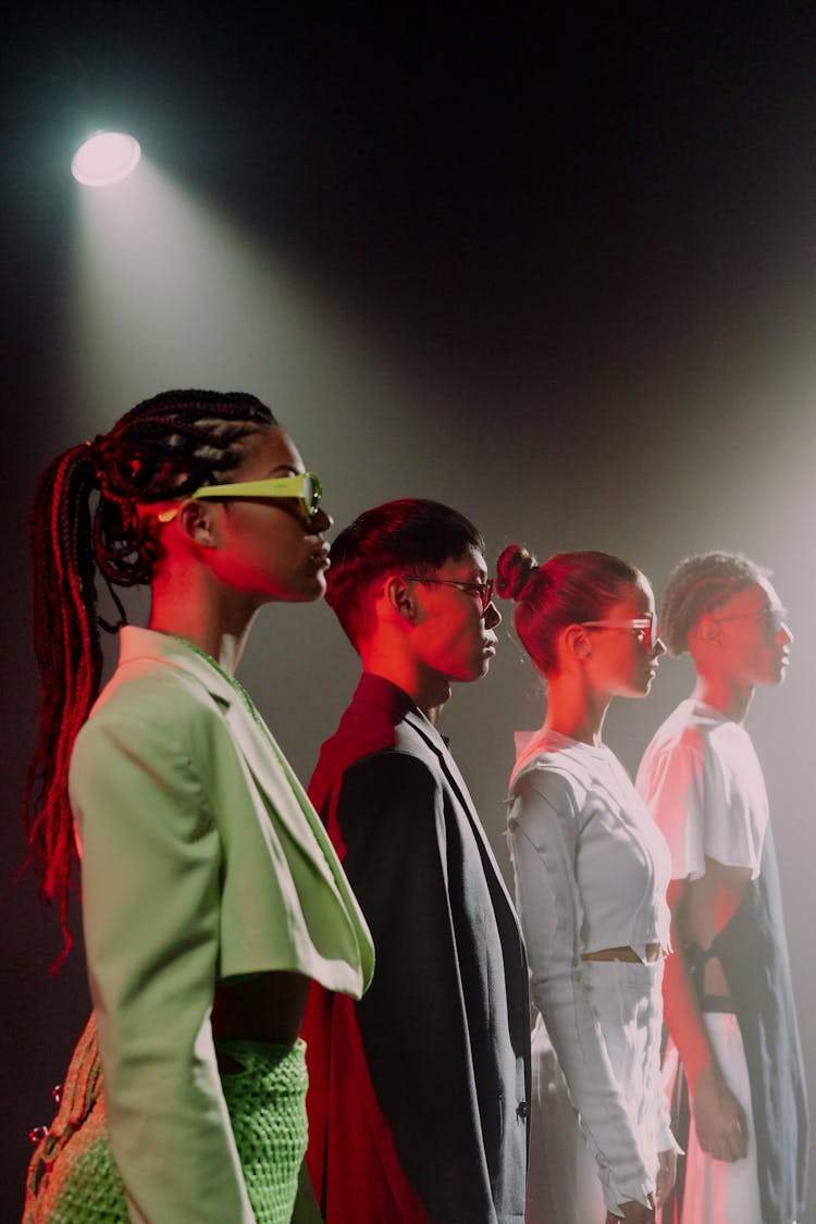 Group Of Young People In Fashionable Clothes And Sunglasses Standing In A Row 