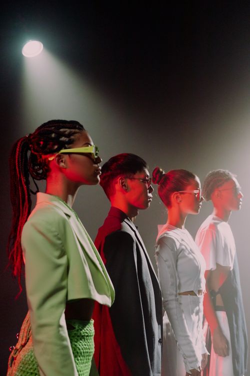 Free A stylish group of young adults in trendy attire posing under a dramatic spotlight at a studio fashion shoot. Stock Photo