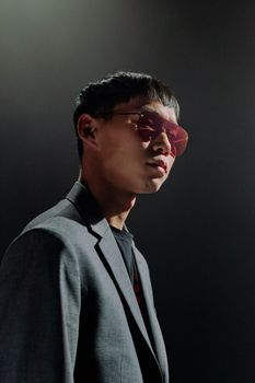 Portrait of a man wearing sunglasses and a suit in a dimly lit studio setting.