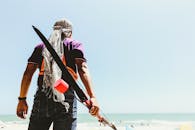 一个人站在海滩上，弯着腰，享受海边明媚的夏日