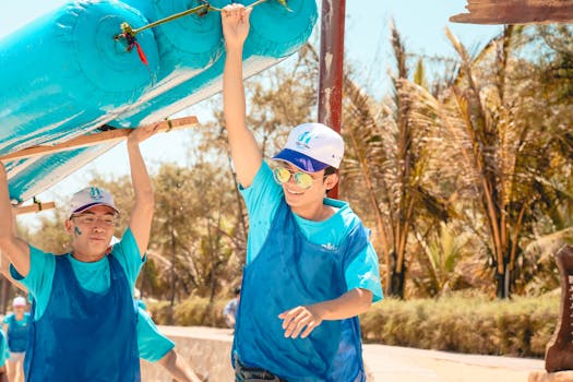 Young adults participate in a fun team-building exercise with inflatable equipment outdoors.