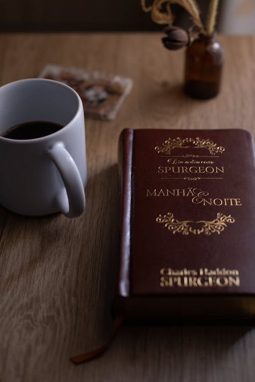 Brown Book Beside White Ceramic Mug on Brown Wooden Table