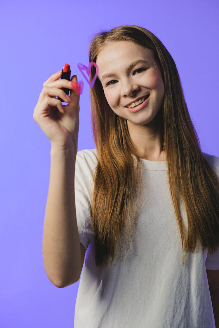 Studio Shot Of Girl Drawing Heart On Glass