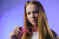 Teenage girl writing No word on glass
