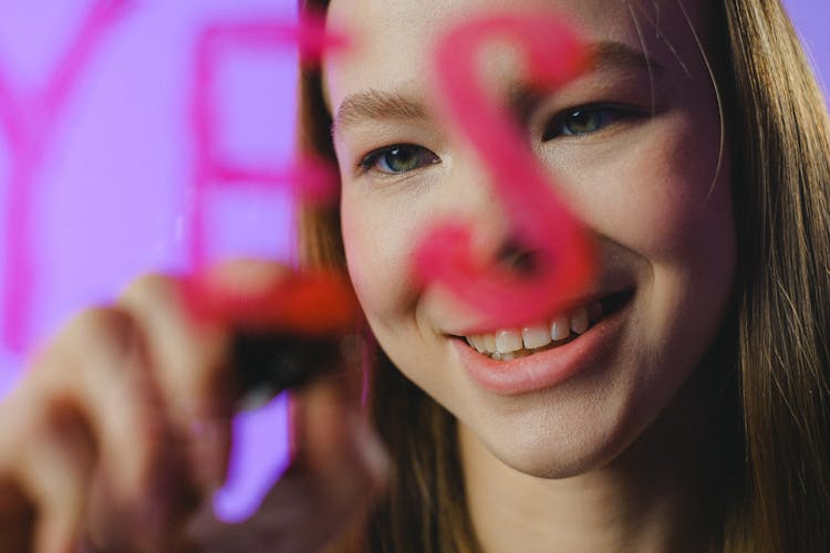 Teenage Girl Writing Yes On Glass