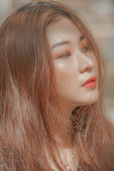 Close-up portrait of a young woman with flowing hair and stylish makeup, exuding beauty and grace.