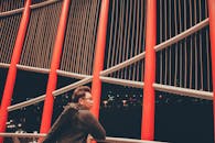 晚上，一名背着背包的男子凝视着现代建筑