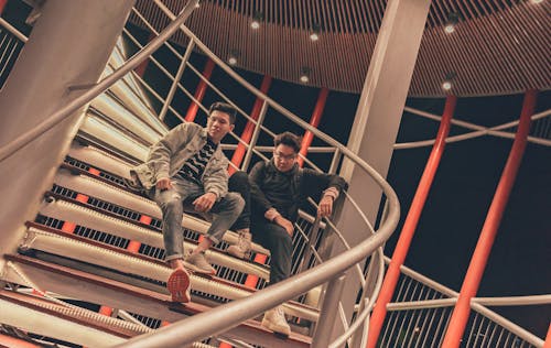 Two Men Sitting on Spiral Stairway