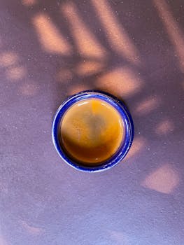 Top view of hot espresso in a blue cup on a textured surface.