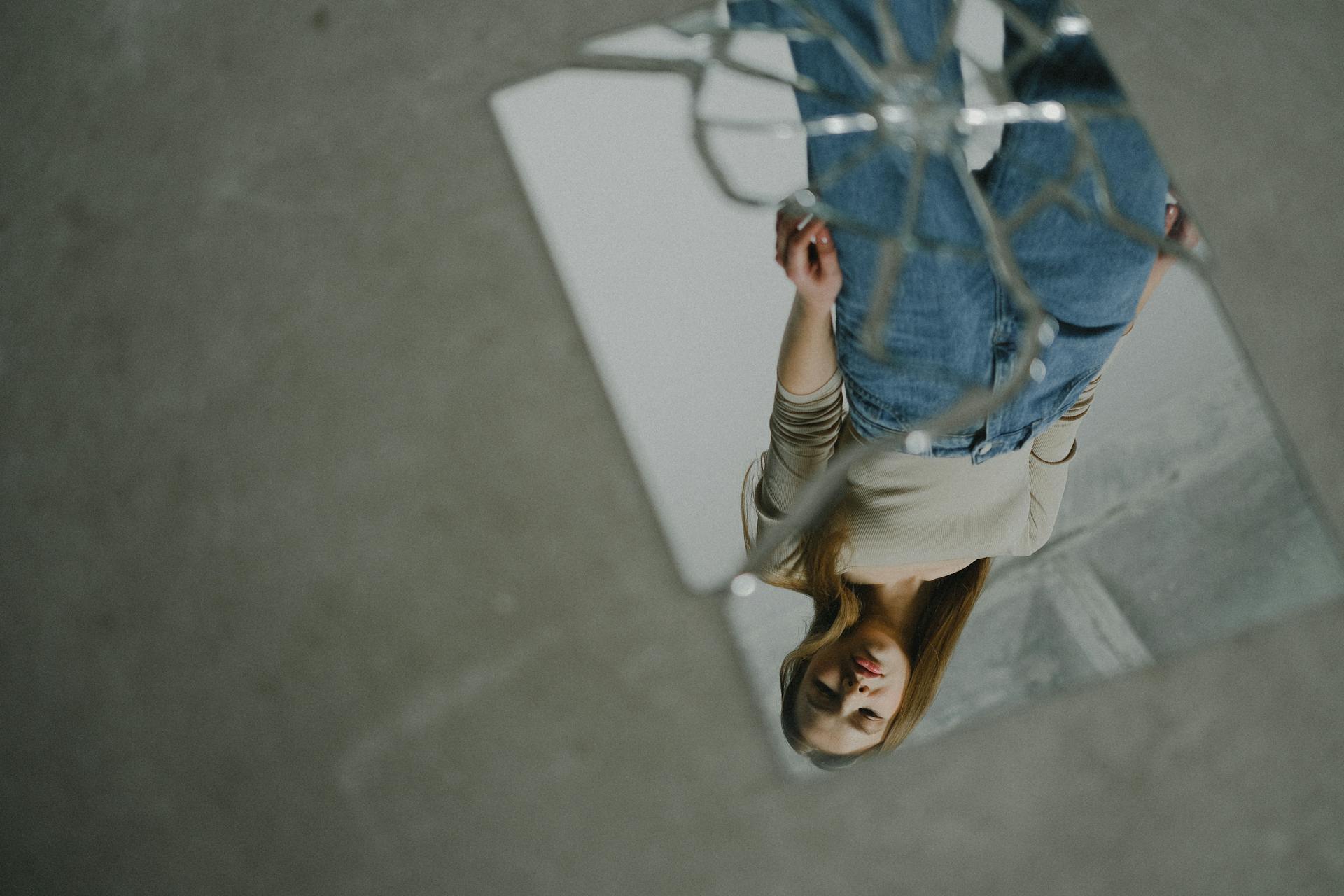 Artistic photo of a teenage girl reflected in a broken mirror, creating a conceptual perspective.