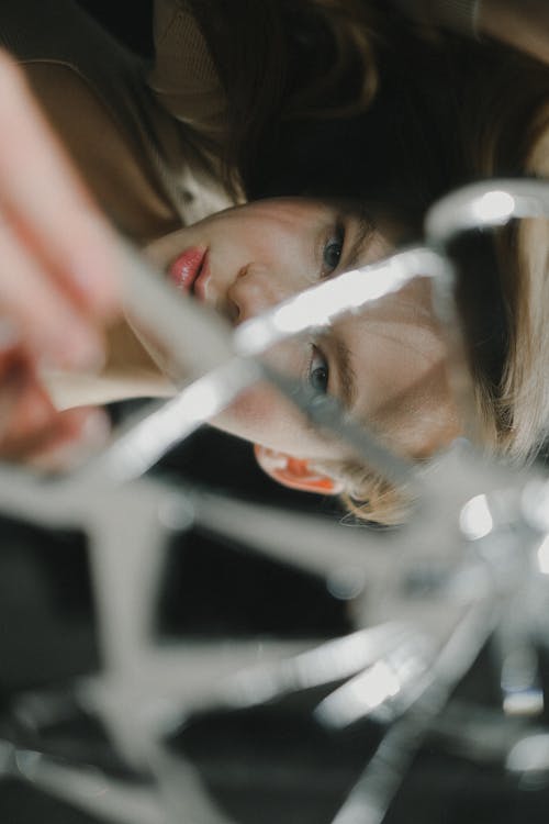 A teenage girl looking at camera through broken mirror 