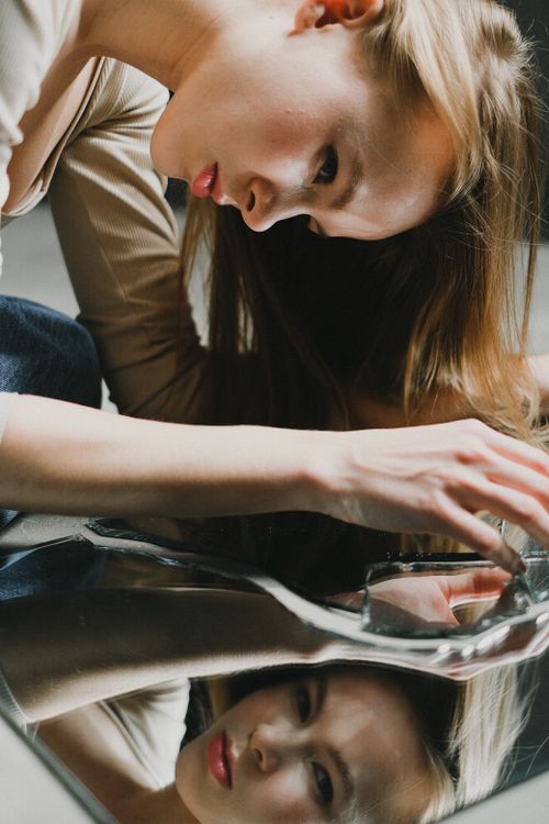 Free Stylish portrait of a woman leaning over a broken mirror, reflecting her image creatively. Stock Photo