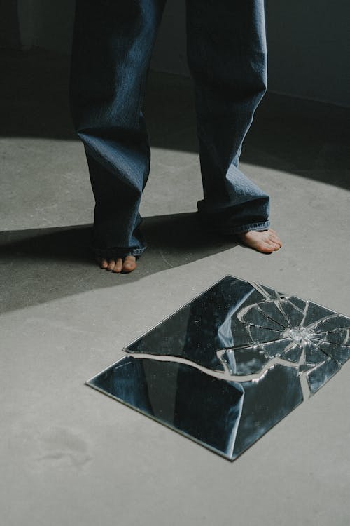 Person standing over broken mirror