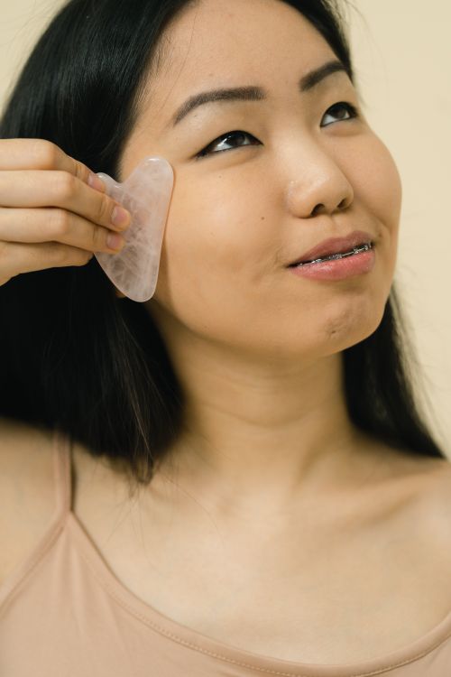 Free A woman using a gua sha tool for a relaxing face massage in a studio setting. Stock Photo