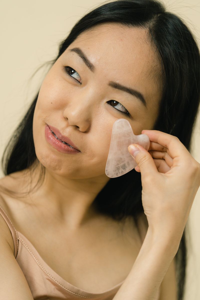 Woman massaging her face with a gua sha stone