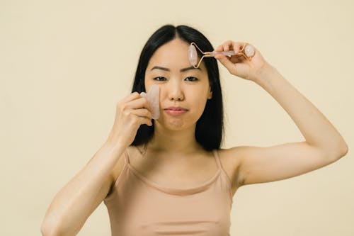 Woman giving herself facial massage with two cosmetic products