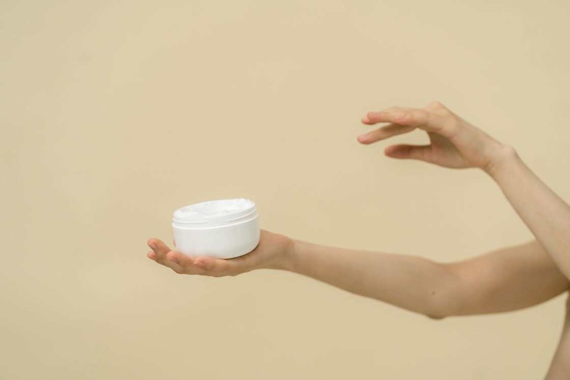 Hand holding an open jar of balm, photo by SHVETS production on Pexels
