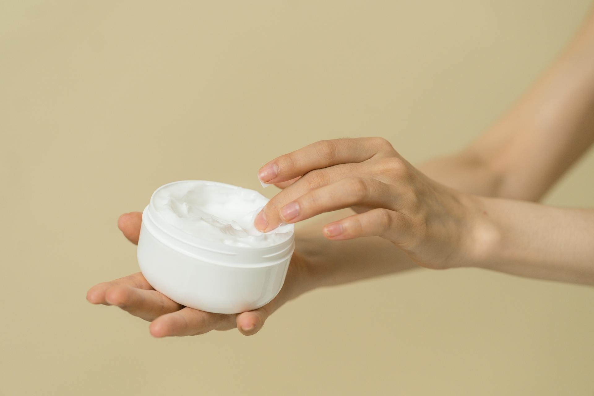 Woman taking cosmetic product from container