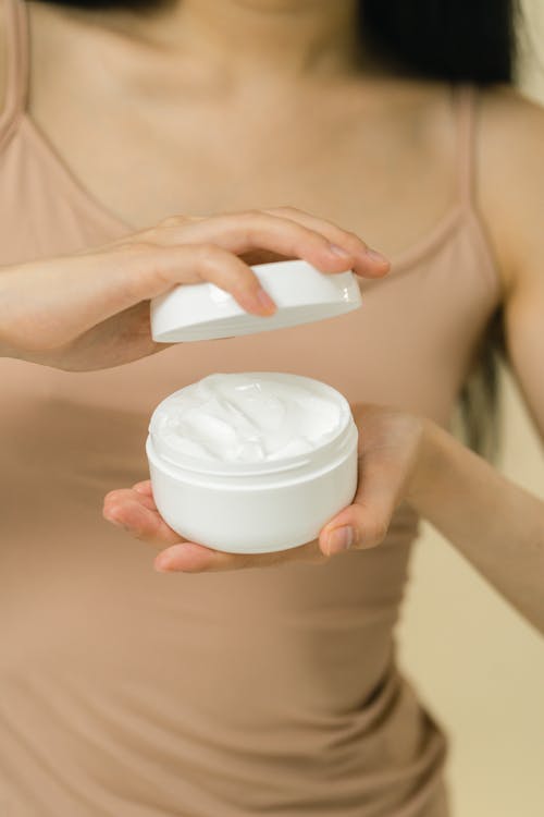 A female hands holding an opened cosmetic cream 