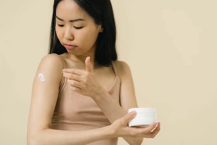 Woman Putting Cream On Her Arm