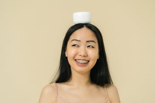Woman balancing cosmetic container on her head
