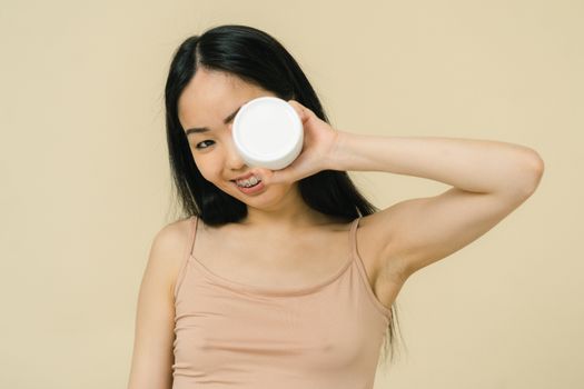 Smiling woman holding aloft cosmetic 